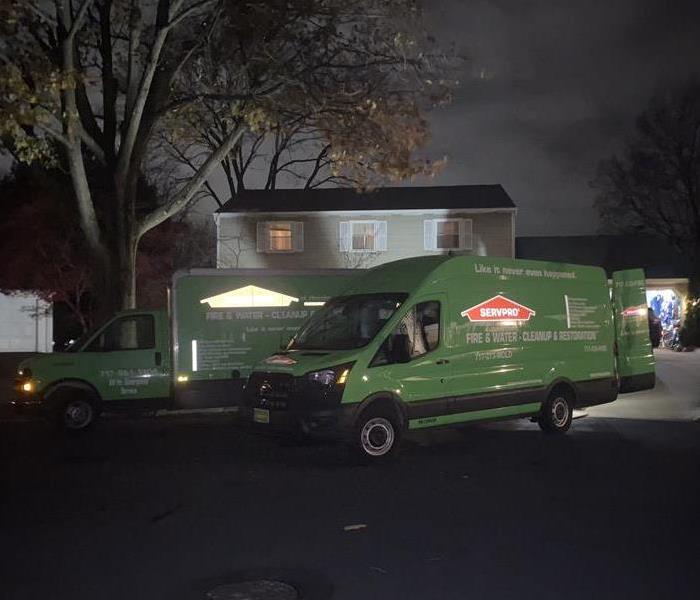 Two SERVPRO vehicles parked in front of a house fire