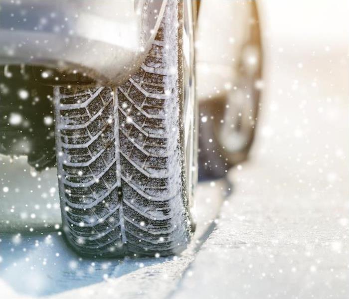 Close-up image of a car and tire moving through snow 
