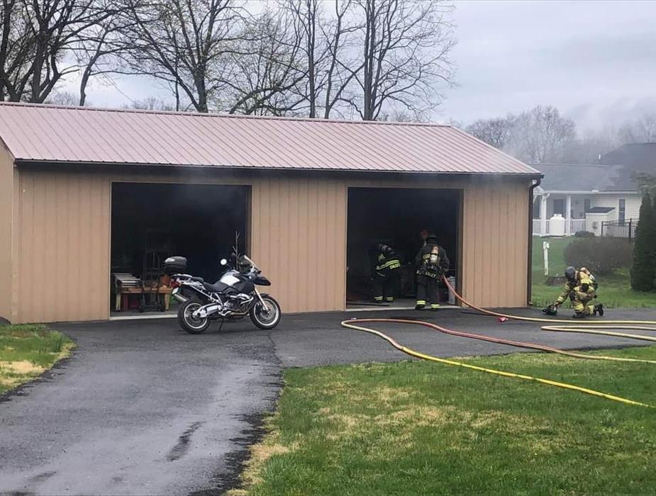 A motor cycle on fire, fireman in scene